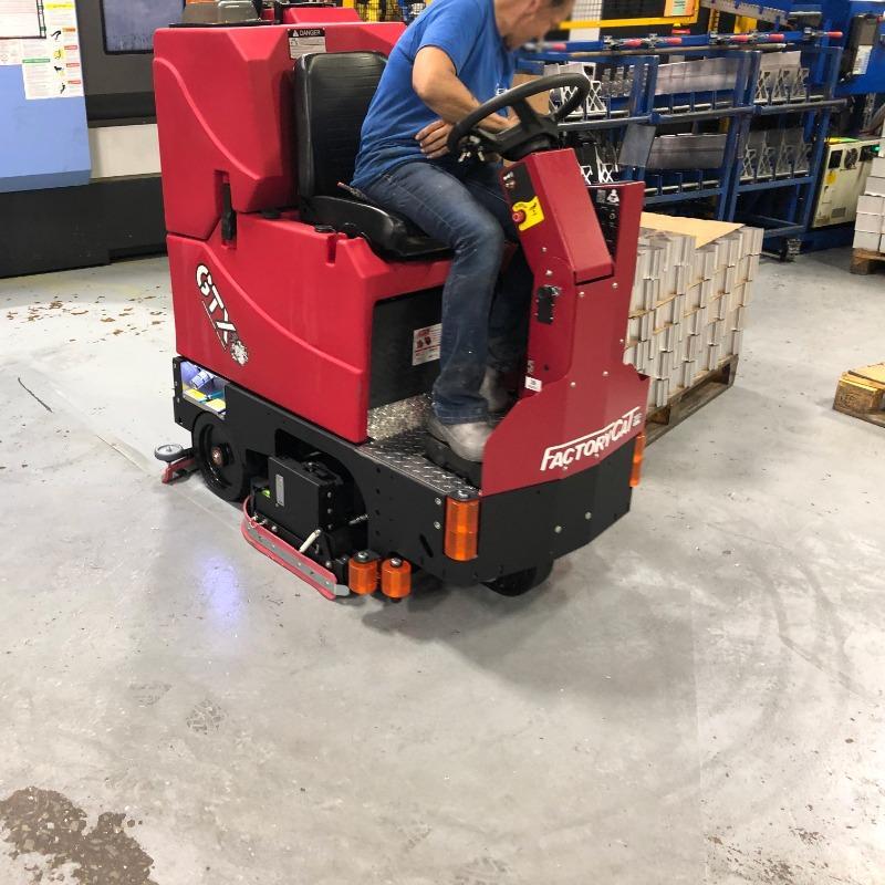 FactoryCat Ride On Floor Scrubbers GTX production floor concrete - https://assets.factorycat.com/demoImages/2025/april/GTX-Ride On Floor Scrubbers-production floor-concrete-Knoxville-USA-817.jpg - 800 - 800 - 817 A FactoryCat GTX Ride On Floor Scrubber is cleaning the concrete floor in a Knoxville, Tennessee fabrication shop